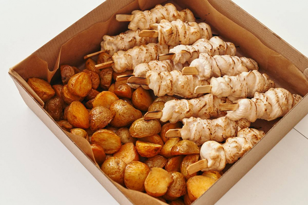 Куриный шашлык с картофелем в коробке для выездного пикника.